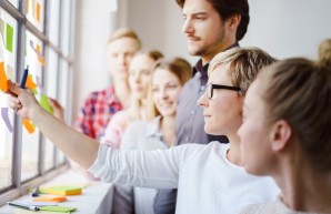 Eine Gruppe von Menschen klebt bunte Zettel auf eine Scheibe