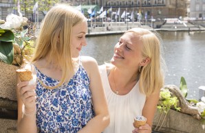 Helen Cohrs steht mit ihrer Schwester eisessend auf einer Treppe, sie lächeln einander an