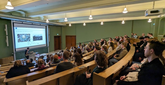 Mit Besucher:innen gefüllter Hörsaal